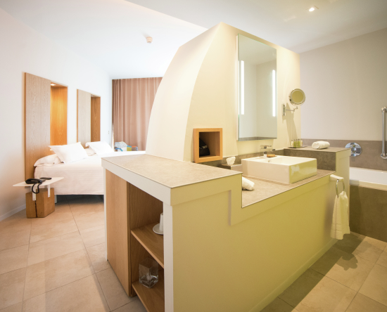 Zimmer mit Kingsize-Bett, Loungebereich, Telefon, Badezimmer mit Spiegel, Toilettentisch und Badewanne